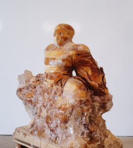 Sculpture figurative en bois et résine époxy Scroll Sequence Phil Meyer. Le personnage se jette en avant, masqué, comme s'il essaie de sortir d'une masse de cristal. Son bras est caché dans un mouvement de drapé.